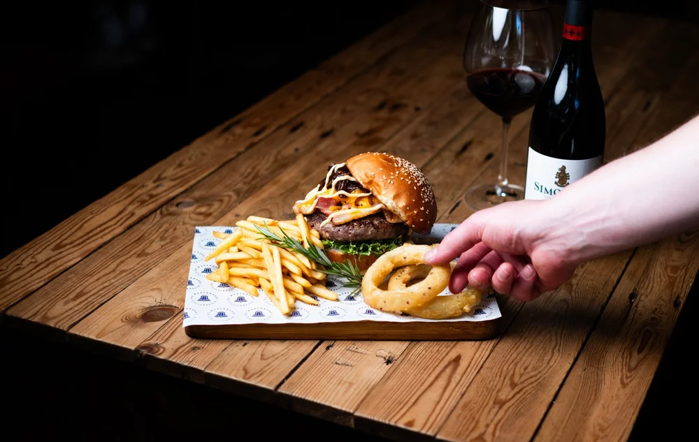 Gourmet burger and fries with a glass of red wine on a wooden table