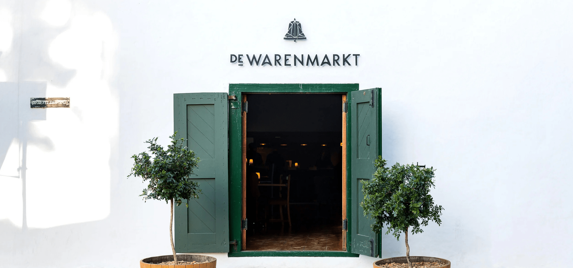 De Warenmarkt entrance with open green doors and bell logo
