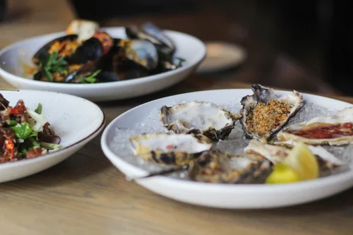 Fresh oysters on ice with lemon, served with mussels and salad