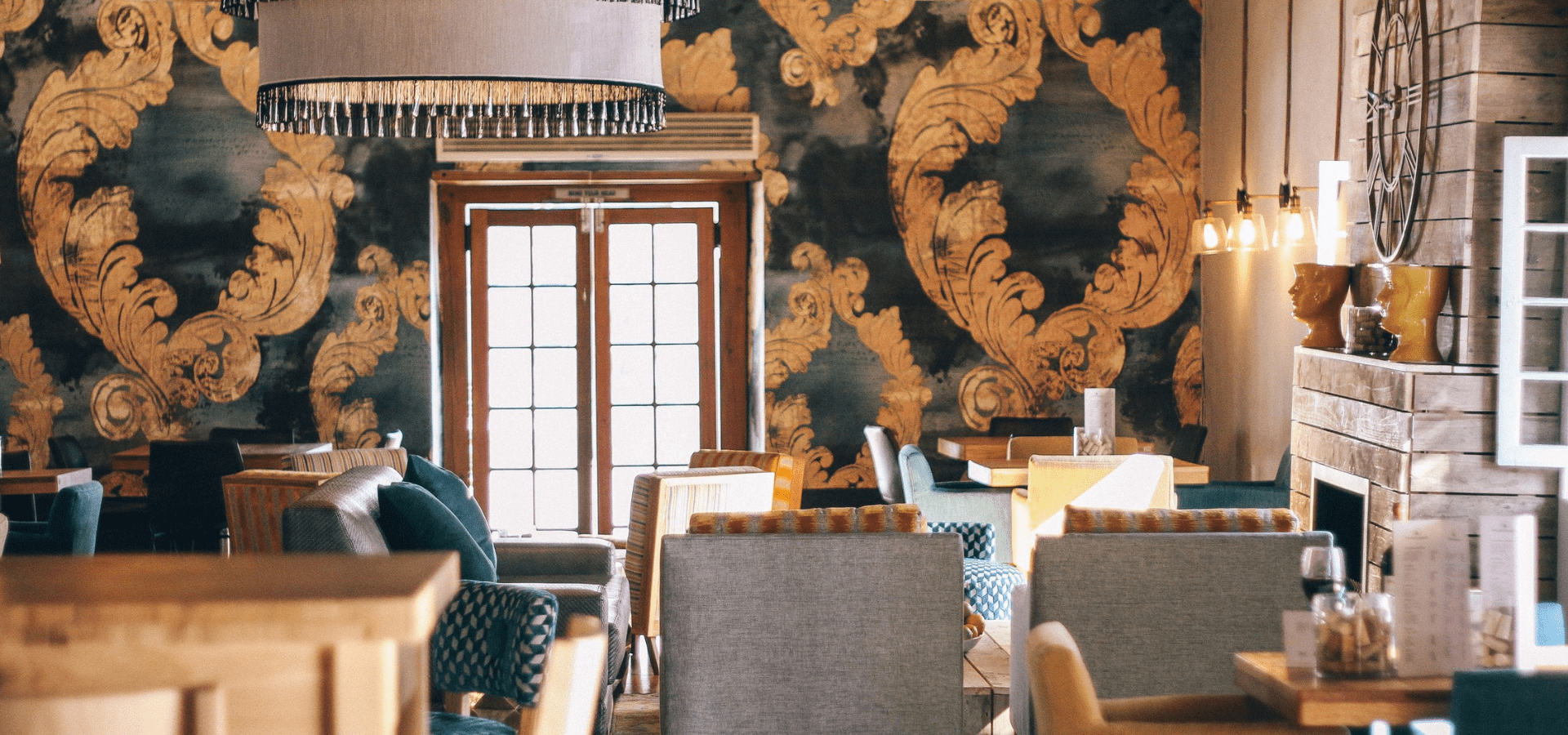Elegant cafe interior with ornate wallpaper, comfortable seating, and warm lighting.