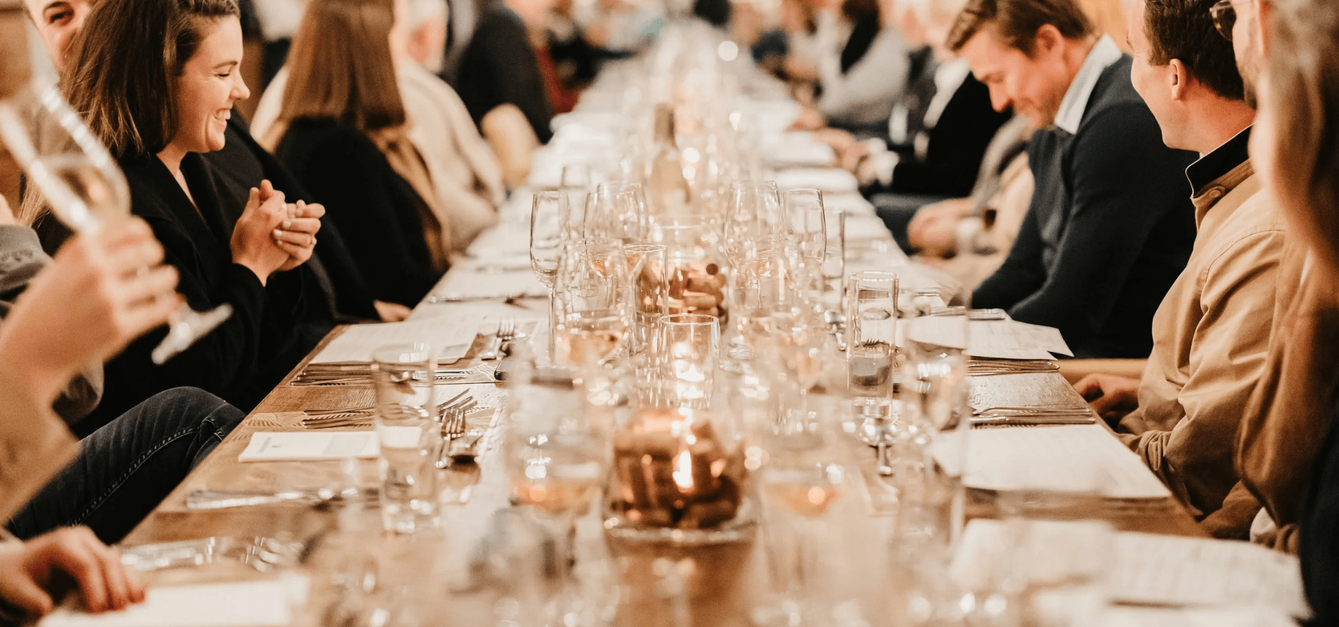 People dining at a long table with candles and wine glasses.