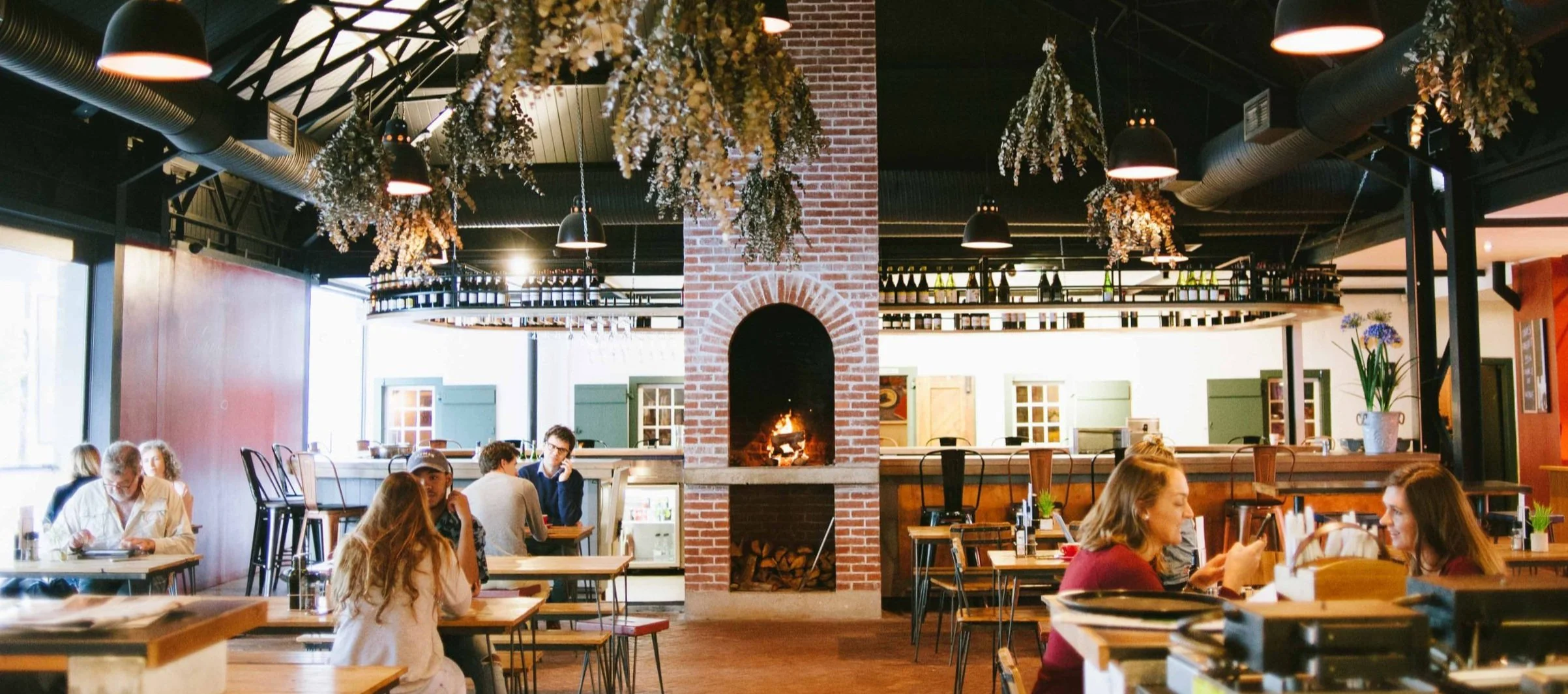 People dining and enjoying a meal in the rustic restaurant with a fireplace.