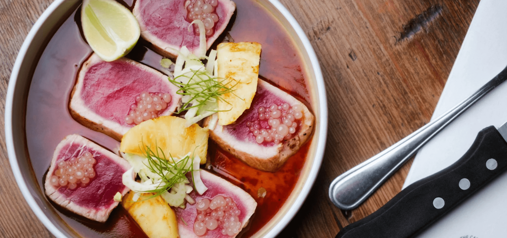 Seared tuna steaks with pineapple, lime, and pickled onions in a red sauce