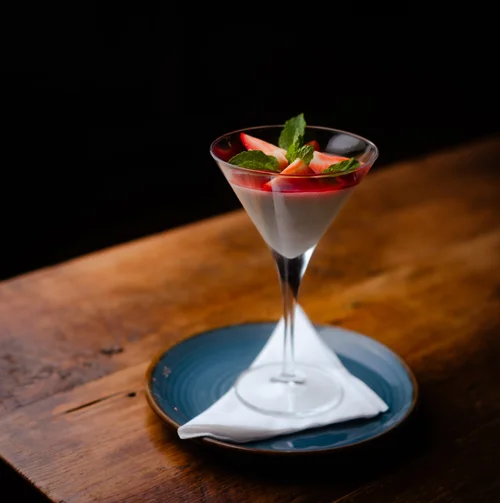 Creamy dessert with strawberries and mint in a martini glass