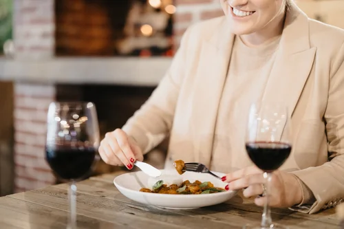 Woman enjoying a meal with red wine, suggesting a restaurant booking experience.
