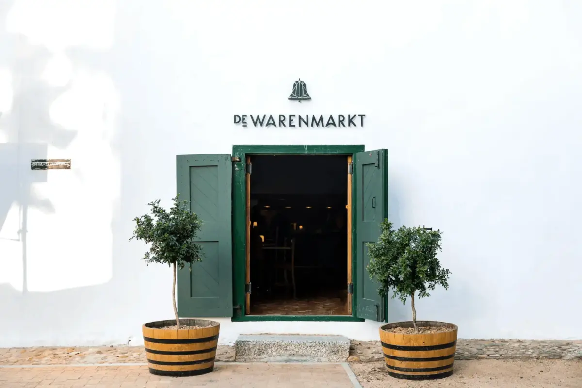 De Warenmarkt building entrance with open green doors and potted trees.
